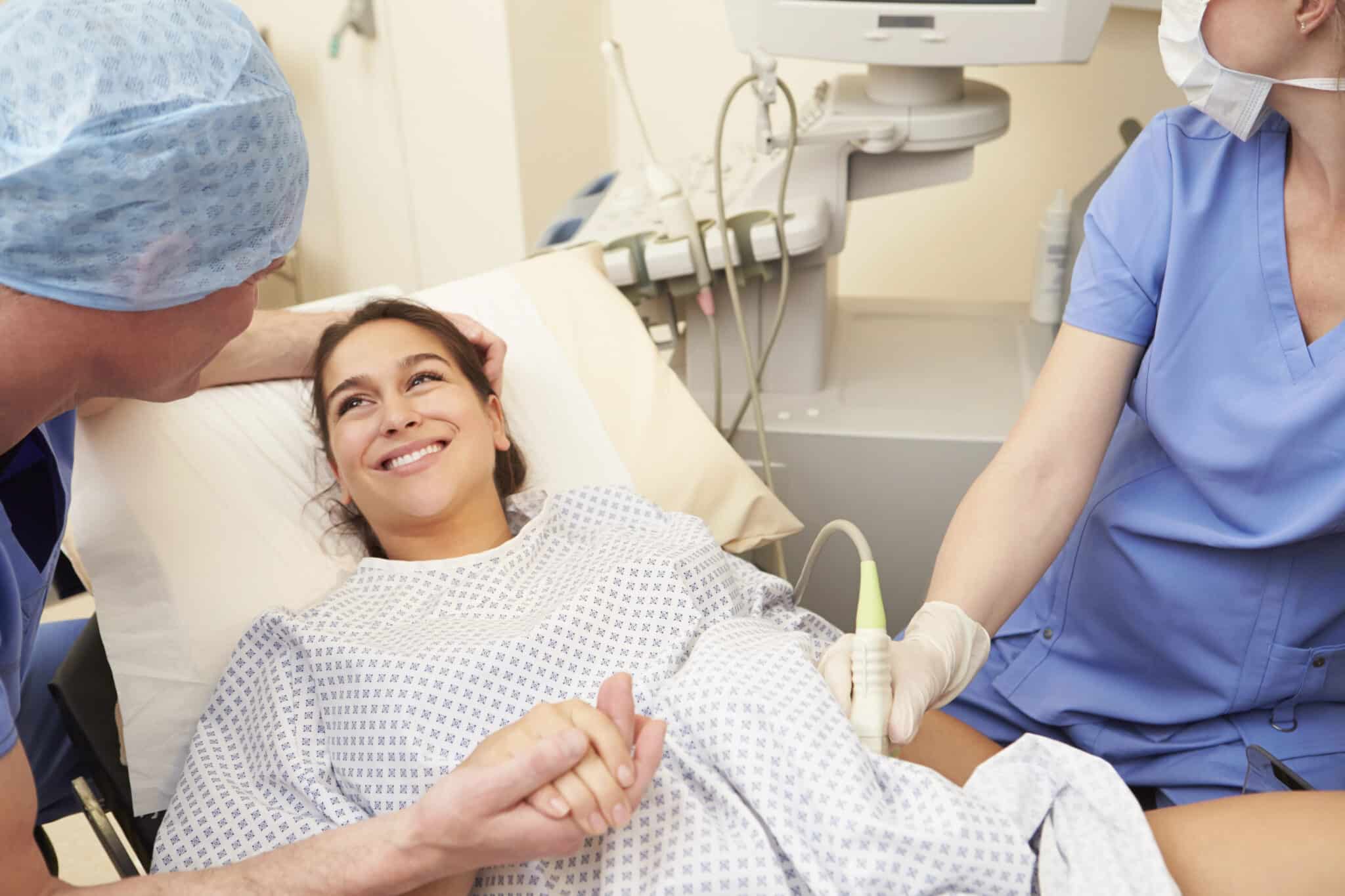 A pregnant woman smiling while talking to obstetricians and gynecologists at a maternity center.